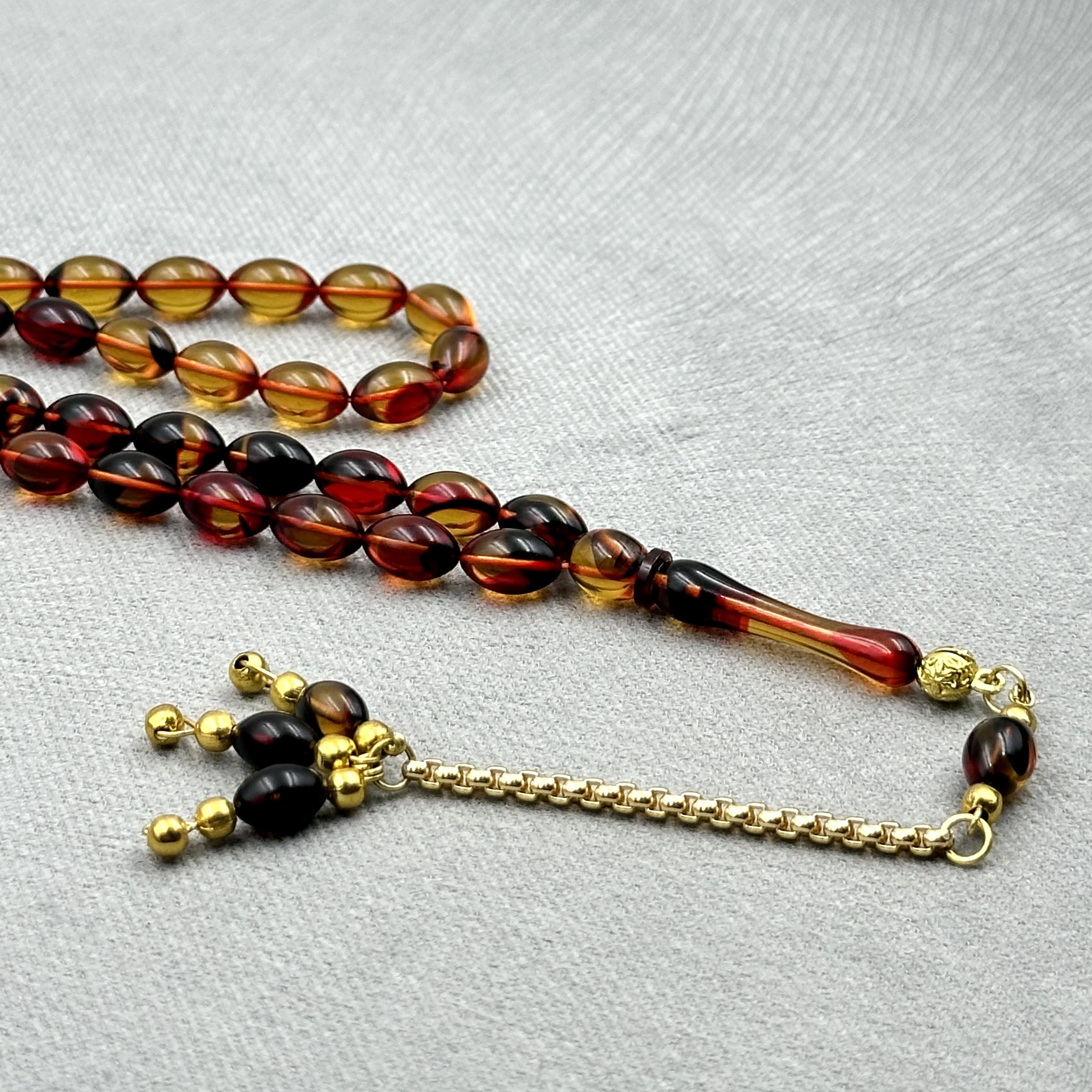 Burak Özecik Usta İşçilikli Yoğun Hare Geçişli Kırmızı Siyah Renk Altın Ton Kaplama Metal Zincir Püskül Detaylı Sıkma Kehribar Tespih