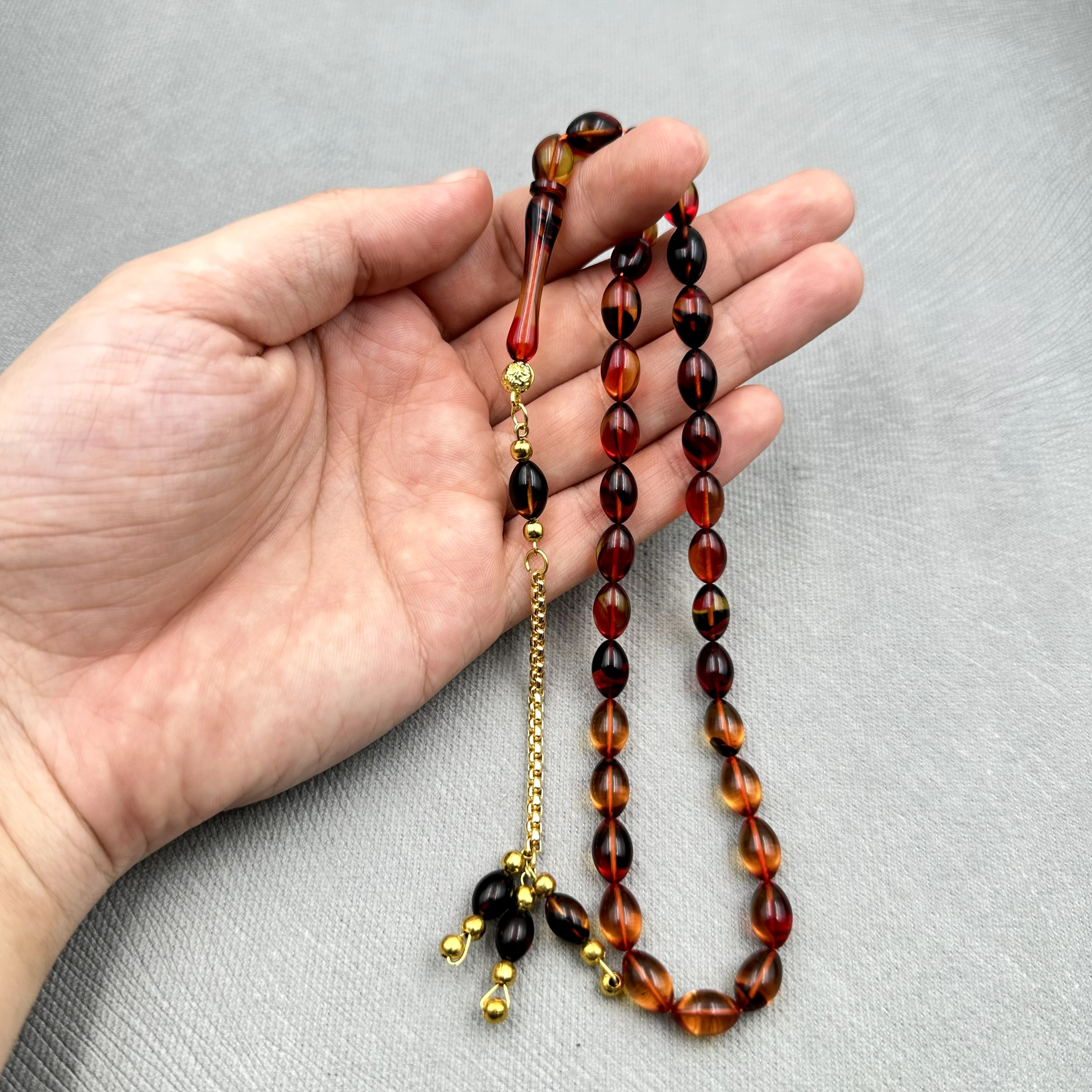 Burak Özecik Usta İşçilikli Yoğun Hare Geçişli Kırmızı Siyah Renk Altın Ton Kaplama Metal Zincir Püskül Detaylı Sıkma Kehribar Tespih