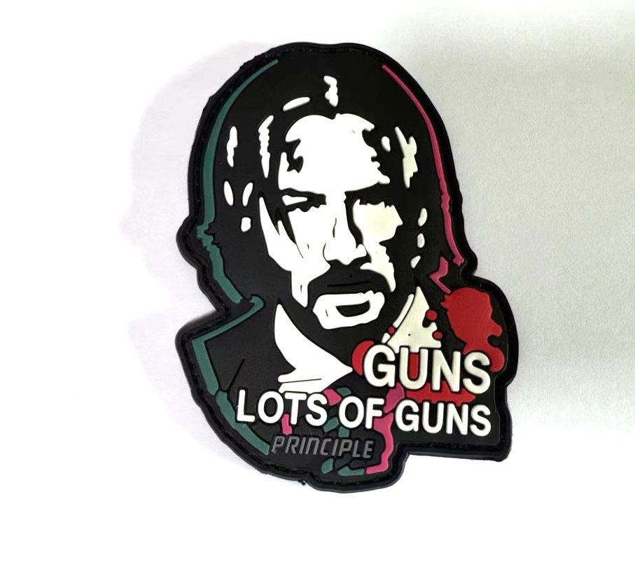 Glow-in-the-Dark Aksiyon Figürlü PVC Patch – “Lots of Guns” Temalı Yama 9.5x7.5 cm