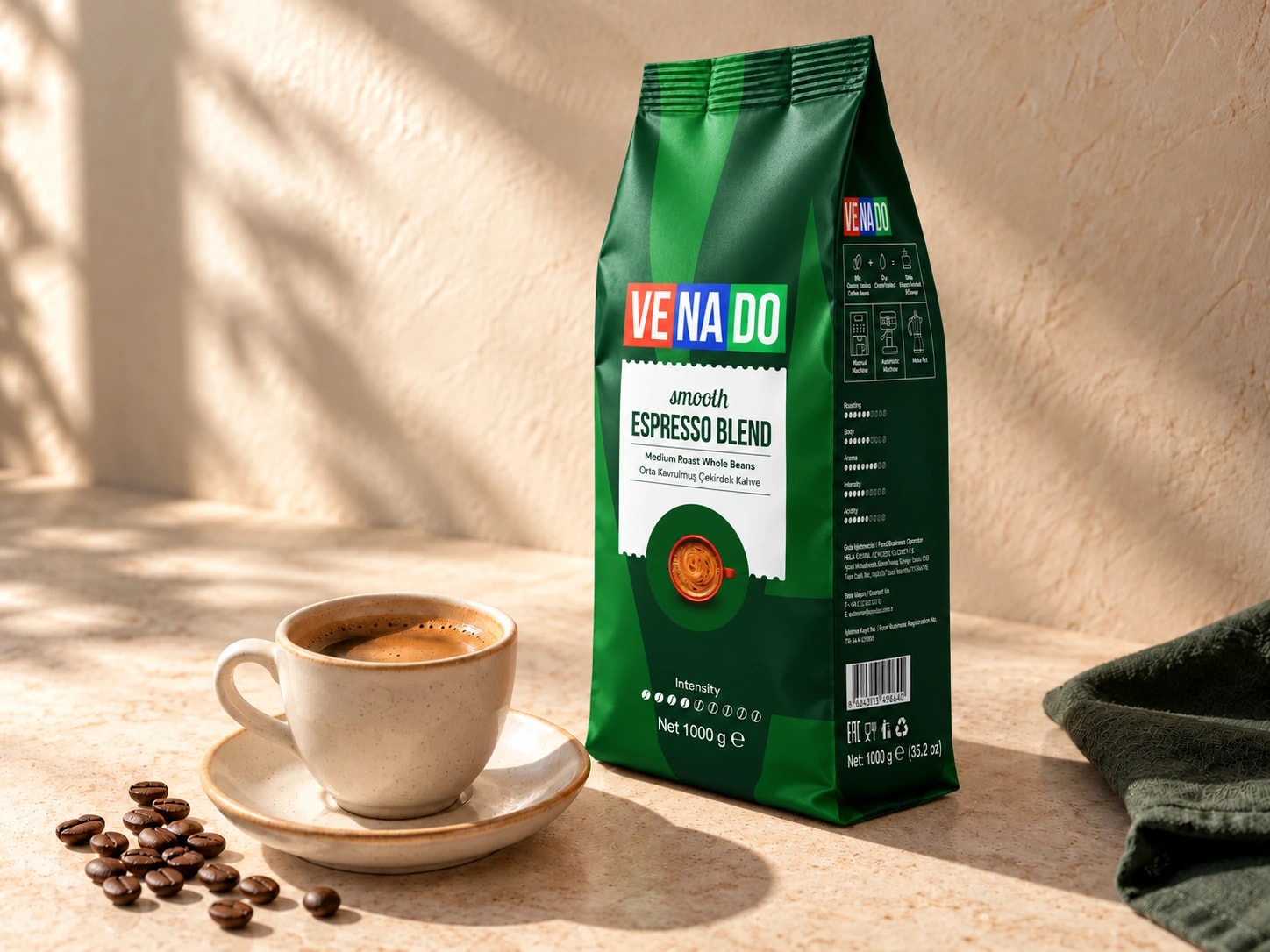 Doğal ışıkta yeni yeşil Venado Smooth Espresso Blend 1000 g ambalajı, seramik fincan ve kahve çekirdekleri