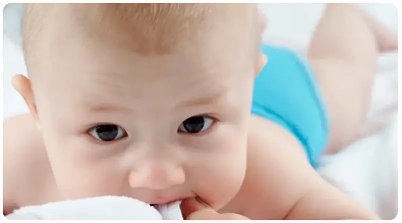 Giysinin kumaşını ve belki de düğmesini kullanıp dişini kaşıyan bir bebek.