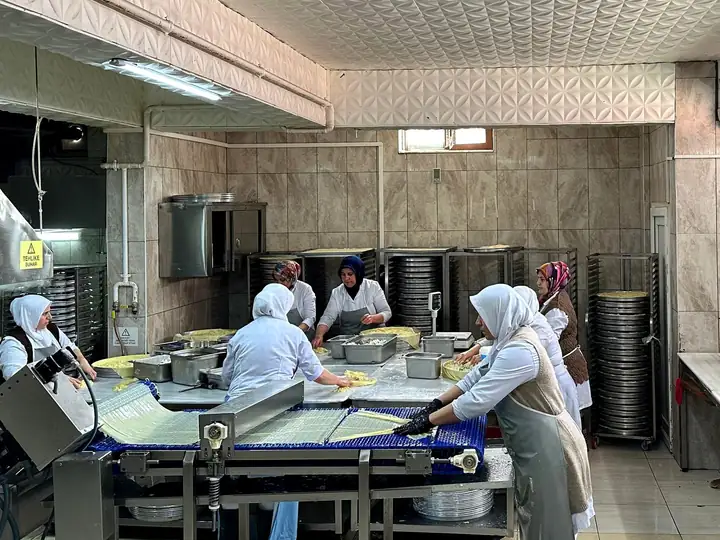 Tepsi Su Böreği üretim ekibi masa başında su böreği hazırlıyor