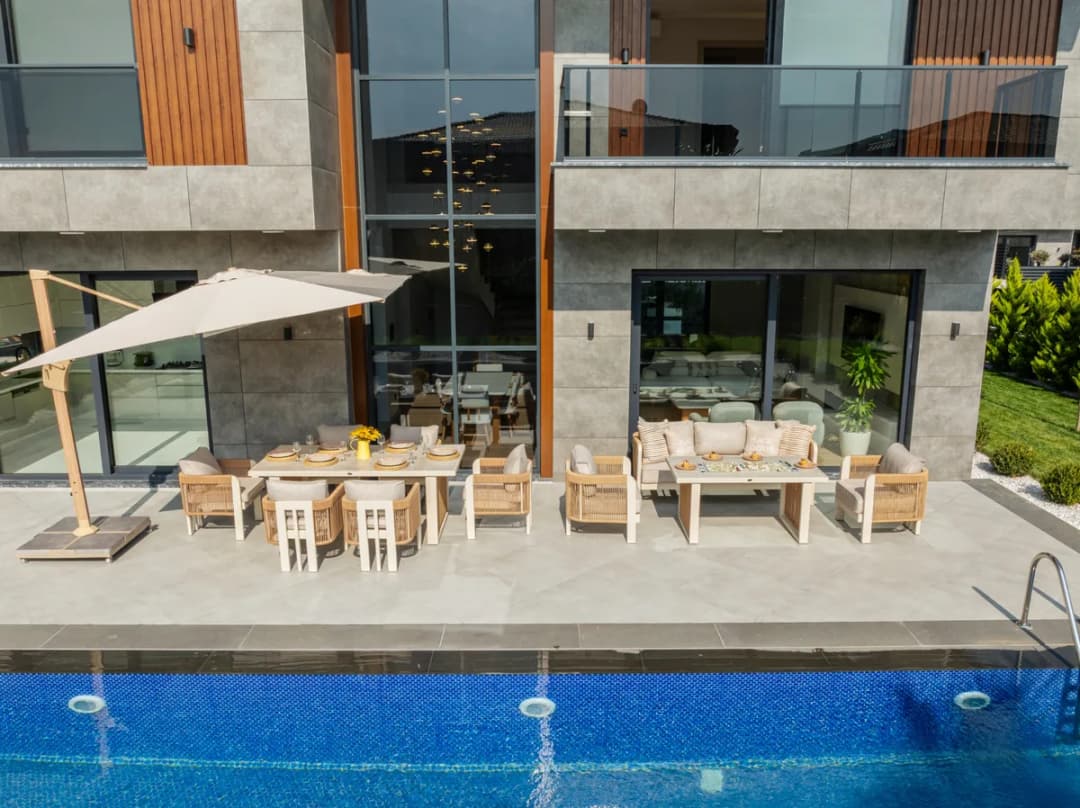 Bahçe oturma grubu ve masa takımı bulunan havuzlu villa terası