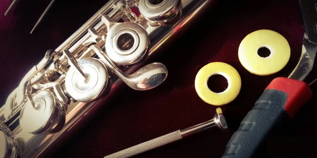 Tamir işlemi yapılan bir yan flüt, tornavida, yedek pedler ve pense.