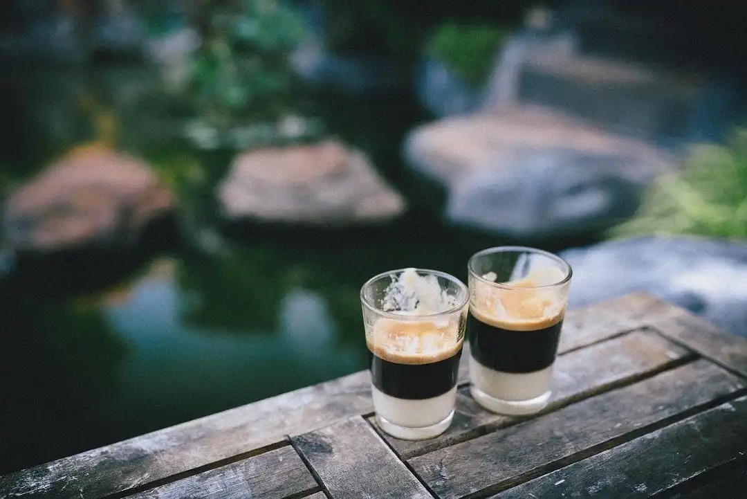 Doğal ortamda ahşap masa üzerinde iki cam bardakta espresso kahve – espresso ve filtre kahvenin kafein oranı karşılaştırması