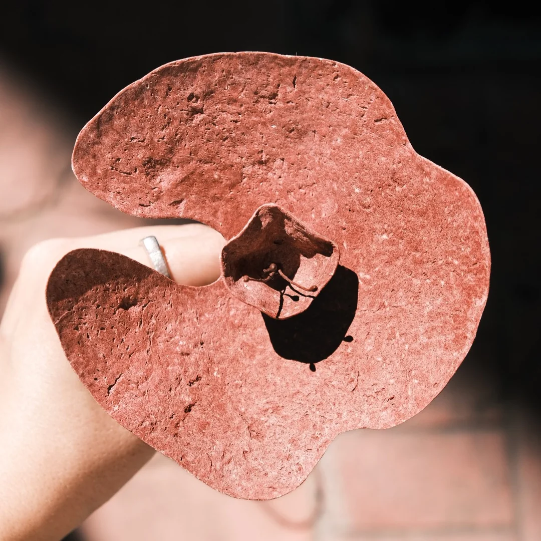 Geri dönüştürülmüş malzemeden üretilmişkırmızı tonlarında upcycled çiçek, yakın plan doku detayı.